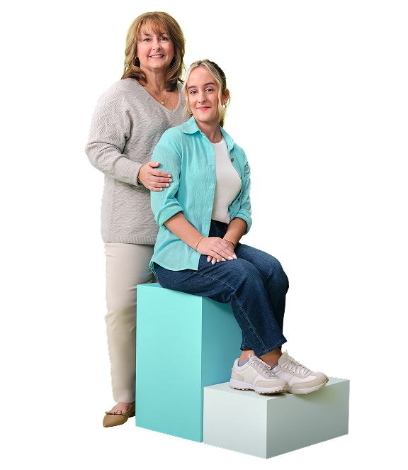 Karabeth, who is living with XLH, sitting down while her mother JoBeth stands behind her with a hand on her shoulder